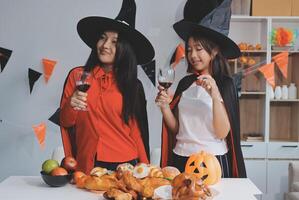 friendship, holiday and people concept - group of happy smiling friends in halloween costumes of vampire, devil, witch and cheetah at home party photo
