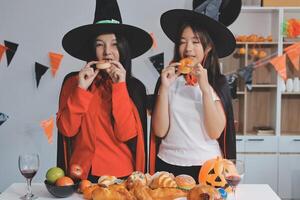 friendship, holiday and people concept - group of happy smiling friends in halloween costumes of vampire, devil, witch and cheetah at home party photo