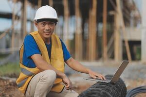 Asian man architect holds blueprint with skyscraper background, Asian male architect builder engineer design working planning confident outdoors in construction site. photo