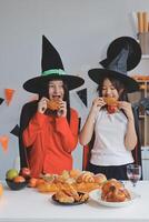 friendship, holiday and people concept - group of happy smiling friends in halloween costumes of vampire, devil, witch and cheetah at home party photo