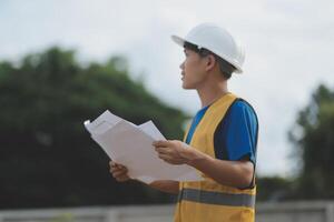 Engineering Consulting People on construction site holding blueprint in his hand. Building inspector. Construction site check drawing and business workflow of new building photo