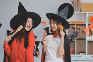 friendship, holiday and people concept - group of happy smiling friends in halloween costumes of vampire, devil, witch and cheetah at home party photo