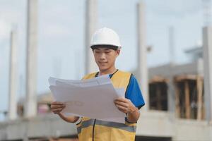 Engineering Consulting People on construction site holding blueprint in his hand. Building inspector. Construction site check drawing and business workflow of new building photo