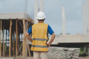 Asian man architect holds blueprint with skyscraper background, Asian male architect builder engineer design working planning confident outdoors in construction site. photo