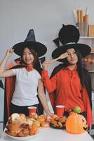 friendship, holiday and people concept - group of happy smiling friends in halloween costumes of vampire, devil, witch and cheetah at home party photo