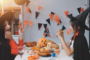 friendship, holiday and people concept - group of happy smiling friends in halloween costumes of vampire, devil, witch and cheetah at home party photo