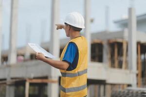 Engineering Consulting People on construction site holding blueprint in his hand. Building inspector. Construction site check drawing and business workflow of new building photo