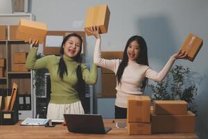 Startup SME small business entrepreneur of freelance Asian woman wearing apron using laptop and box to receive and review orders online to prepare to pack sell to customers, online sme business ideas. photo