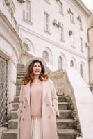 woman in elegant coat and hat against an intricate architectural backdrop, harmoniously blending modern fashion with historical allure. The soft daylight adds to its timeless appeal. photo