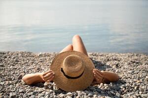 A woman is laying on the beach wearing a straw hat. She is relaxed and enjoying the sun. photo