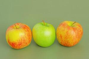 Two red and yellow apples and one green apple. Fruit, apples on a green background. photo