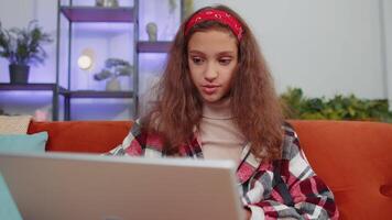 Girl sitting on home couch, looking at camera, making conference call with friends or family video
