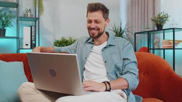 hombre sentado en hogar sofá, mirando a cámara, haciendo conferencia llamada con amigos o familia video