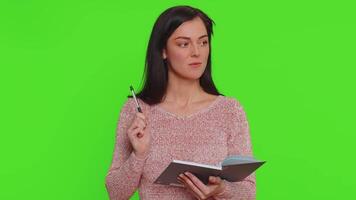 Thoughtful journalist woman making notes, writing down thoughts with pen into notepad notebook diary video