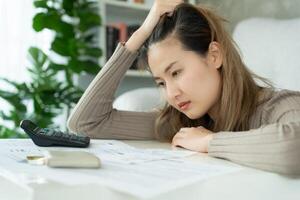 Stressed and headache asian woman with large bills or invoices no money to pay to expenses and credit card debt. shortage, Financial problems, mortgage, loan, bankruptcy, bankrupt, poor, empty wallet photo