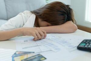 Stressed and headache asian woman with large bills or invoices no money to pay to expenses and credit card debt. shortage, Financial problems, mortgage, loan, bankruptcy, bankrupt, poor, empty wallet photo