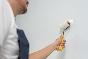 painter man, brush in hand for products to restore and paint the wall, indoor the building site of a house, wall during painting, renovation, painting, contractor, Architect, construction worker photo
