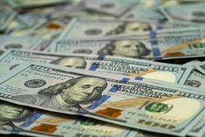 Close-up view of stacked hundred dollar bills on a flat surface photo