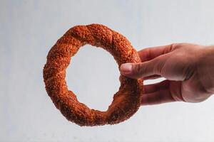 Delicious sesame bread ring held by a hand in clear background photo