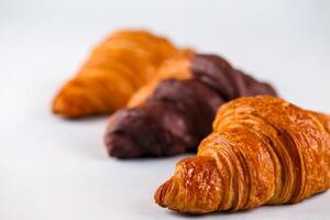 Freshly baked croissants lined up on a plain surface in a bakery photo
