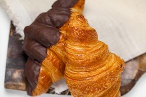 Freshly baked croissants with chocolate drizzle on wooden board photo