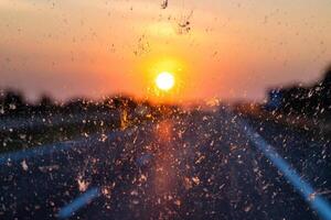 Blurry highway through a smudged dirty car windshield, affecting visibility during sunset, emphasizing highway traffic safety concerns and the importance of clean glass for safe travel. photo