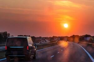 Scenic highway at sunset with minivan and cars and trucks driving through a dirty windshield. Concept of travel, transportation, freedom and the beauty of evening skies on the open road. Copy space photo