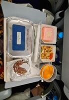 Mecca, Saudi Arabia on 21 February 2024.In-flight meal tray with fried fish asam, dessert, and drink on an airplane. photo