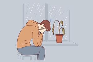 Depressed man sits alone and suffers from melancholy in room with window and wilted flower vector