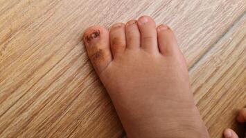 Close-up of a Child's Dirty Foot on a Wooden Floor photo