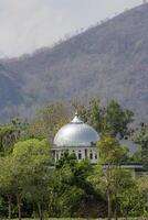 The dome of the mosque stands out from behind the trees against the backdrop of the hills. photo