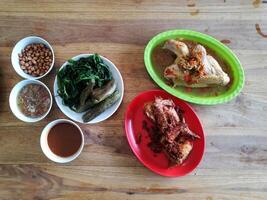 Flat lay view of Ayam Betutu with some vegetables and chili sauce, a typical Balinese dish in the form of steamed or grilled chicken with rich spices photo