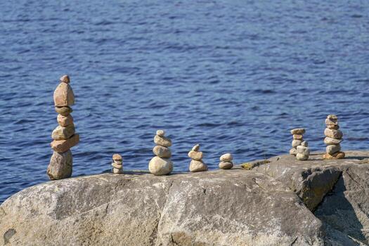 ocho pirámides de piedras en un grande roca en contra el fondo de agua. foto