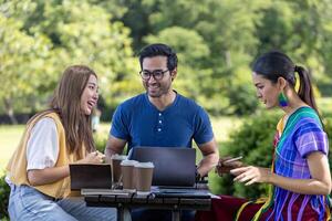 Group of diversity college student is meeting and working on thesis and project outside in the university campus garden during summer photo