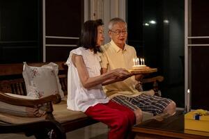 Senior asian couple is celebrating birthday together at home for love, relationship, bonding, longevity and marriage concept photo