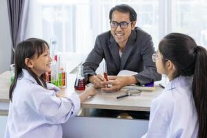 School teacher and young students in scientific lab gown are learning about elements while studying science lesson in the classroom for education, literacy and tutoring concept photo