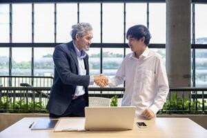 Senior asian executive manager is handshaking with the new trainee employee during probation to pass on knowledge and experience for new generation business inspiration, education and academic photo