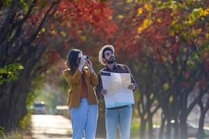 Happy caucasian couple walking together in the public park during autumn with maple and beech tree while looking at camera photo for fall color travel destination and family happiness