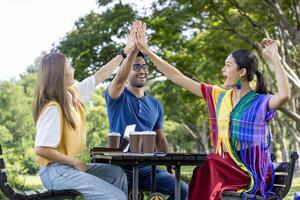 Group of diversity college student is meeting and working on thesis and project with high five in the university campus garden during summer photo