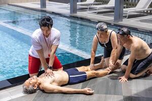 Life guard is doing CPR to the drowning asian senior man at sport club with the family support for accident and emergency medical procedure service and life insurance photo