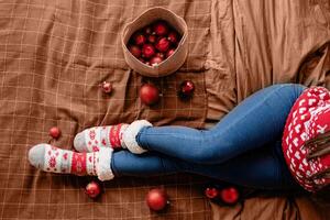 Mocha Mousse - color of the year 2025. Top view female legs with christmas socks on the bed with decorations photo