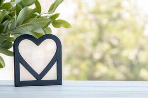 Photo frame of heart shape for mockup design on light table background.