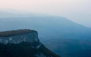 Dawn in the mountains of Crimea. light haze of mist over the mountains and rays of the sun through the clouds. photo