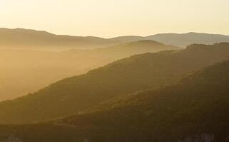 Dawn in the mountains of Crimea. light haze of mist over the mountains and rays of the sun through the clouds. photo