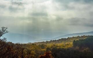Dawn in the mountains of Crimea. light haze of mist over the mountains and rays of the sun through the clouds. photo