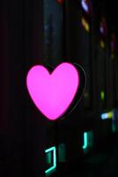 A stunningly vibrant pink heart neon sign captivatingly placed within an urban city environment photo