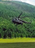Helicopter MI-8 lands on edge in the woods in mountains. photo
