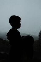 silhouette of a child against the background of a window with raindrops photo
