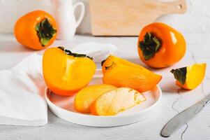 Sliced ripe fresh persimmon on a plate on the table photo