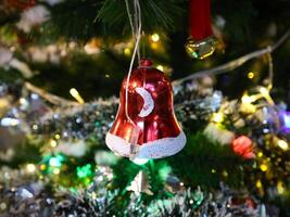 A red bell hanging from a christmas tree photo